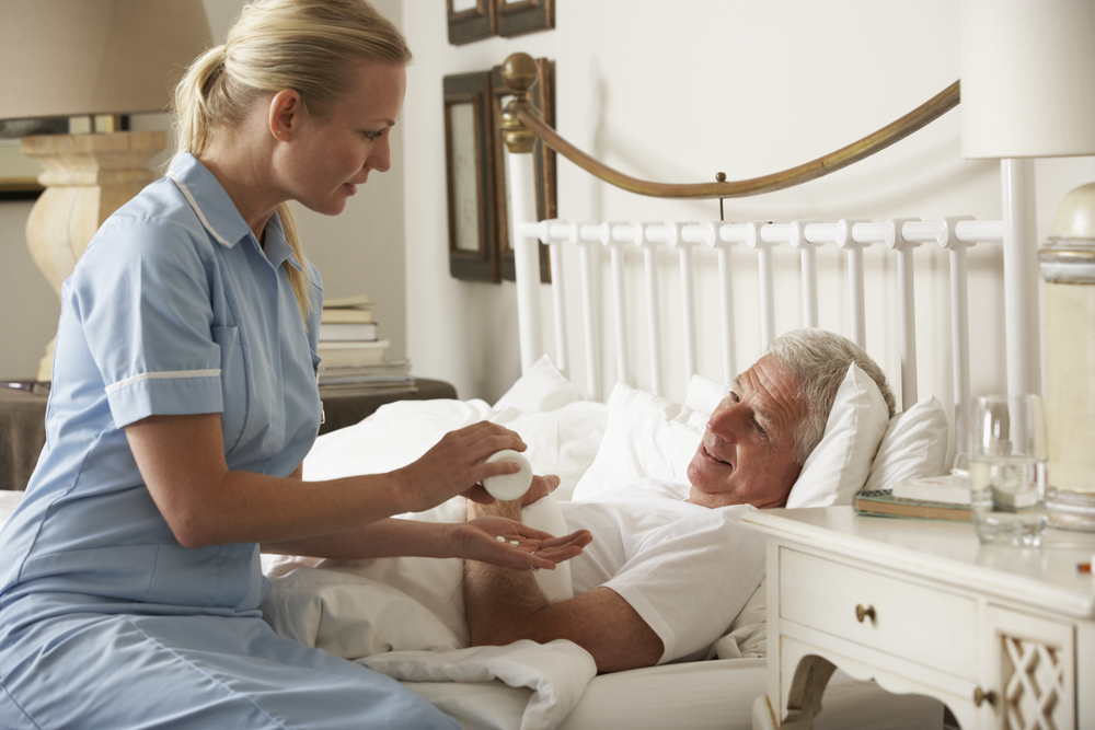 nurse-giving-senior-male-medication-bed